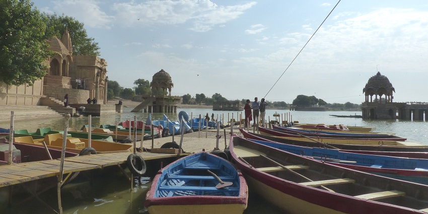 A scenic view of Gadisar Lake with ancient temples and ghats in the background.