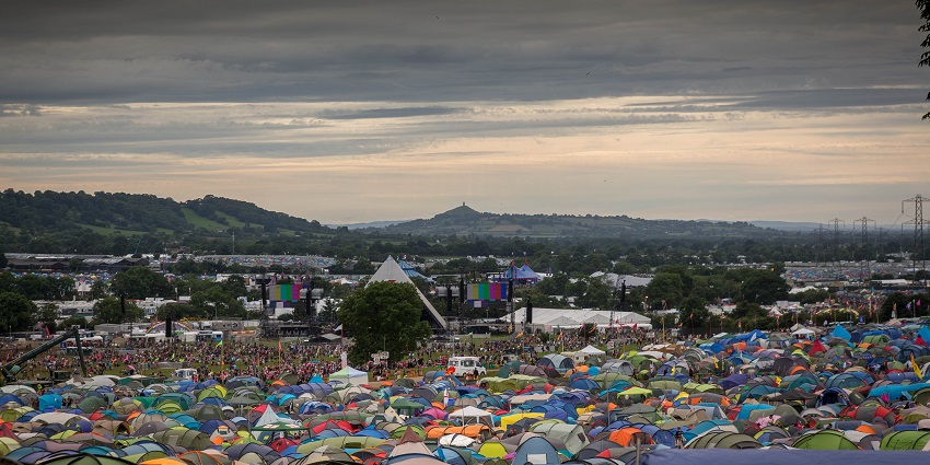 Glastonbury festival from above with camping tents, distant festival, stages and hills