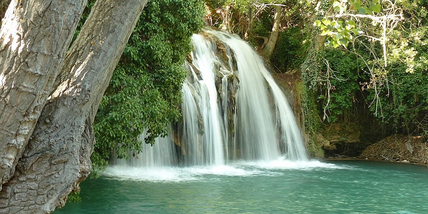 Multiple white streams of Los Chorros Waterfalls are flowing into a turquoise blue pool.
