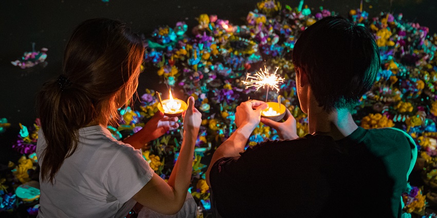 A couple with decorated candles in their hand during the Loy Krathong festival at night