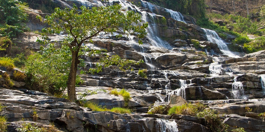 Small cascades fall through step-like rocky structures at Mae Ya Waterfall in Thailand.