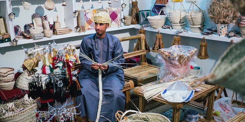 Oman man making and selling traditional handmade crafts at the Muscat Festival.
