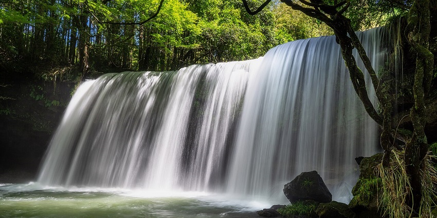 Beautiful Nabegataki Falls with curtain-like water flowing over a rocky cliff in Japan