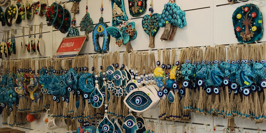 Bright blue evil eye amulets are displayed on keychains and wall hangings in souvenir shops.