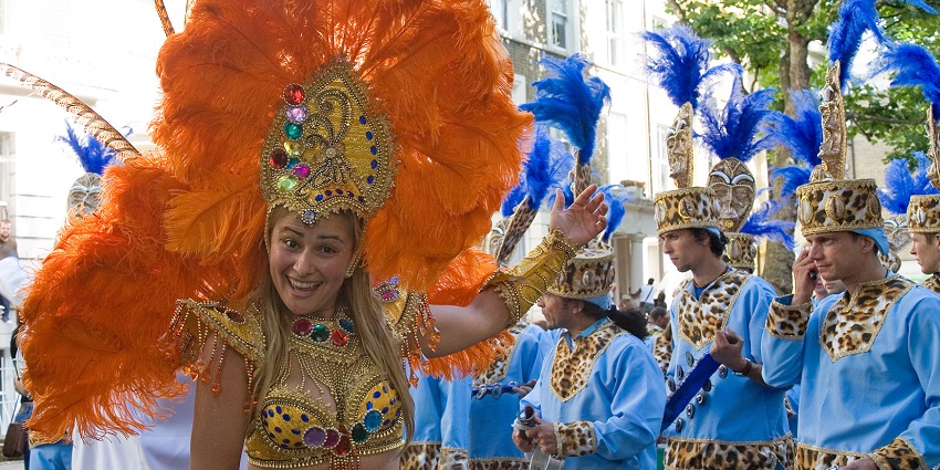 Parade participants dressed in flamboyant costumes adorned with purple feathers