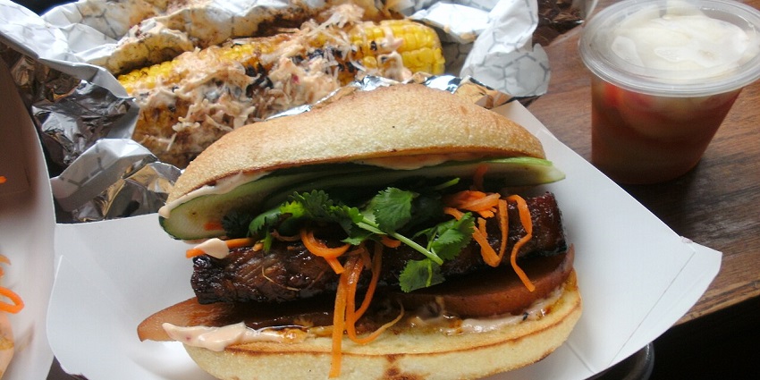An image showing a view of Num Pang, a Cambodian sandwich filled with meat, pickles and herbs.