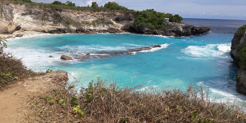 Aerial shot of serene places to visit near Bali with a white-sand beach with clear waters.