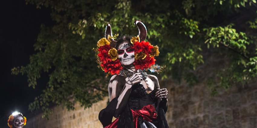People wearing a costume with painted faces and bodies and ears covered by flowers
