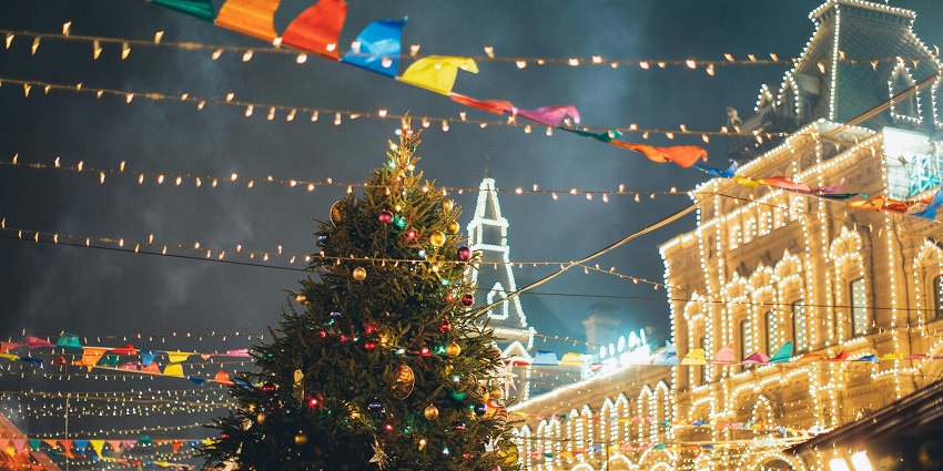 A decorated Christmas tree with glowing lights and red baubles indoors during nighttime
