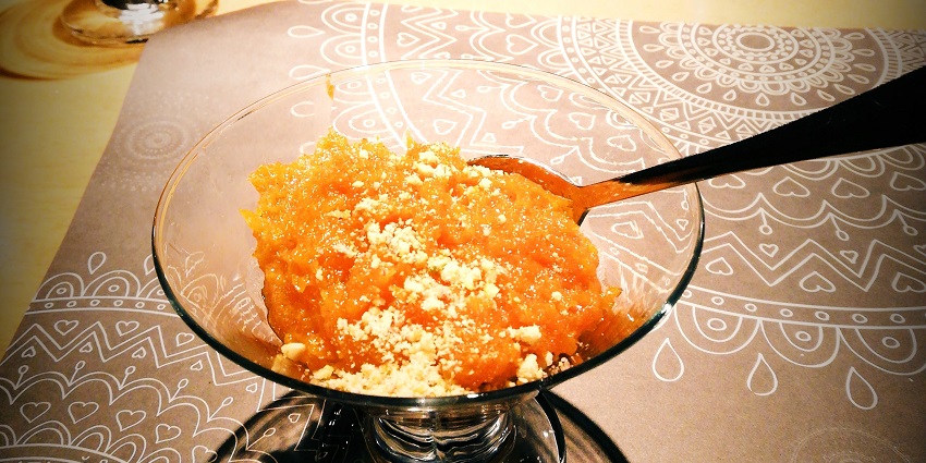 Traditional Oman with things to buy in Omani halwa in a metal tray, rich in colour with visible spices and nuts.