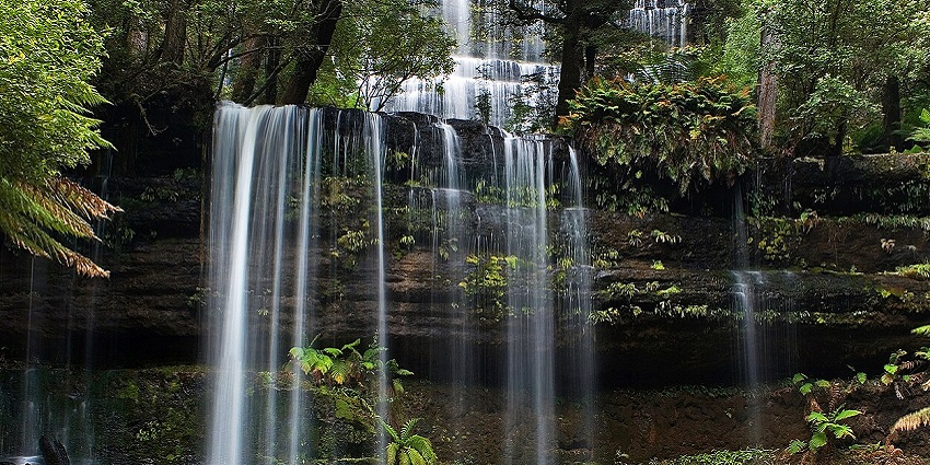 Oropendola Waterfall cascading into a natural pool surrounded by lush greenery.