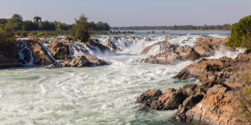 Image of a cascading waterfall through the rocks under clear blue sky day time