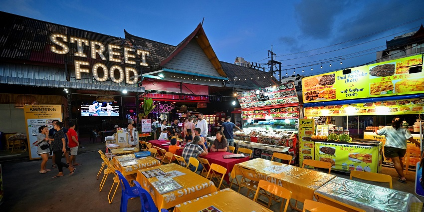 Bustling view of Pa Tong Beach in Phuket with tourists and a street food corner.