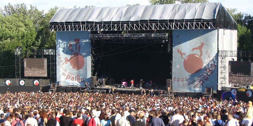 A large crowd attends the Paléo Festival in front of a big outdoor concert stage.