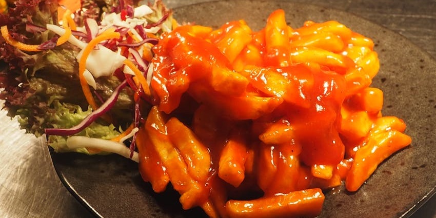 An image showing a vegetable side dish served on a brown plate, similar to papas chorreadas.