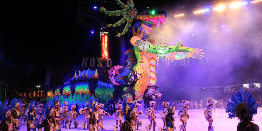 People dressed in vibrant costumes performing with a huge display of a mythological creature