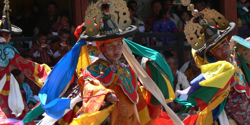 Monks in colourful robes perform the Black Hat Dance for Paro Tshechu, wearing black hats.
