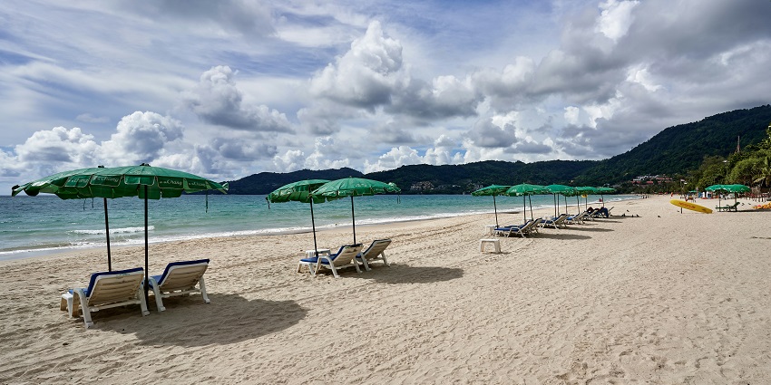 Stunning view of a sandy beach with lawn chairs and umbrellas - places to visit in phuket in july