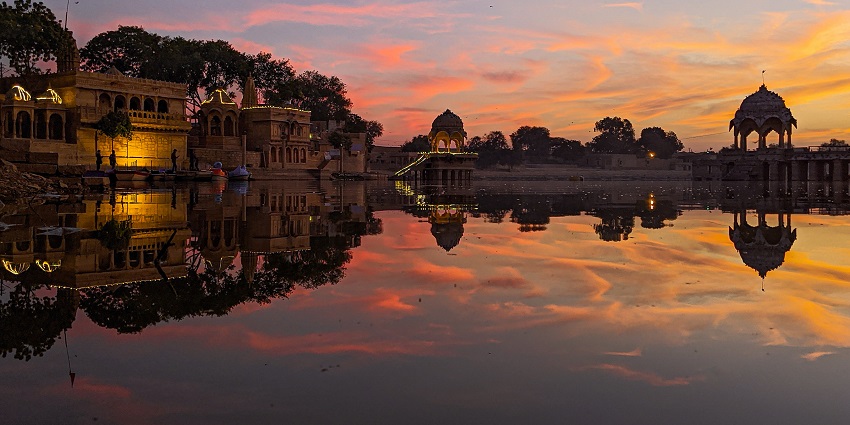 Landscape of a Jaisalmer lake at sunset with beautiful colours of the sky reflecting in the water.