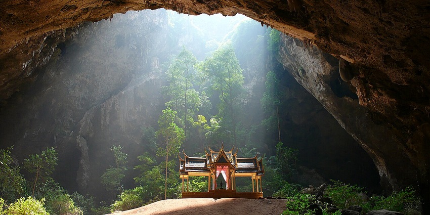An image of Phraya Nakhon Cave in Thailand with sunlight streaming onto a shrine.