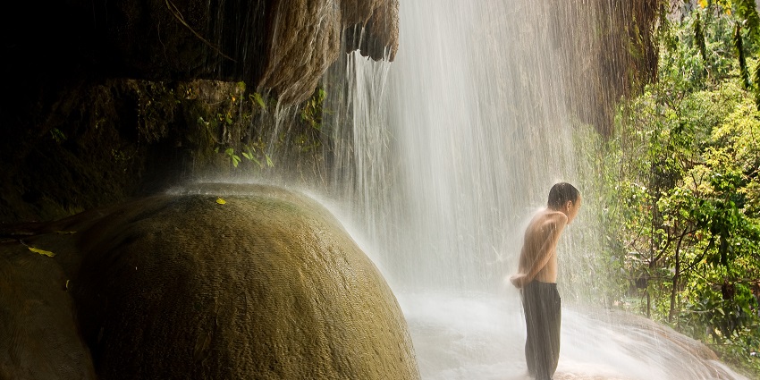 Phu Sang National Park features lush forests, serene waterfalls, and a warm spring-fed stream flowing from a cliff, offering peaceful nature experiences in northern Thailand.