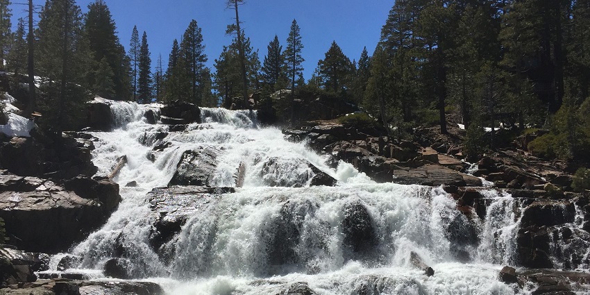A beautiful view of a waterfall dropping down from a mountain into a water body.