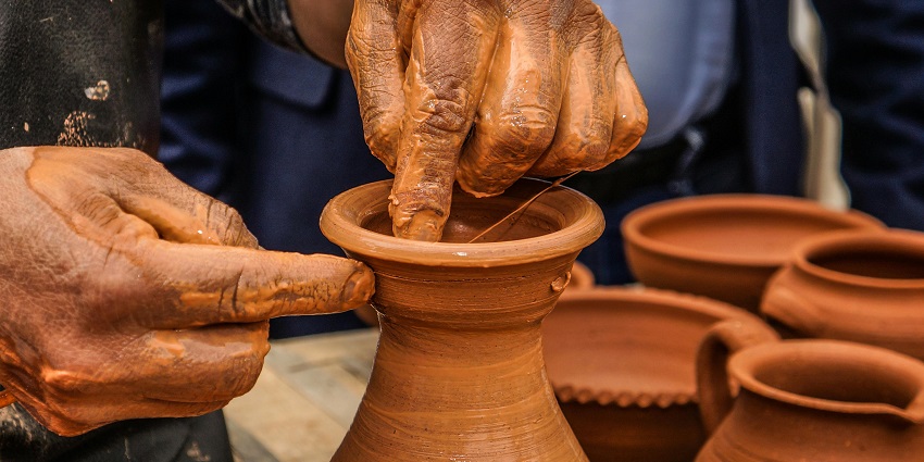 Stacks of unglazed clay pots and jugs displayed at a pottery stall in natural daylight.