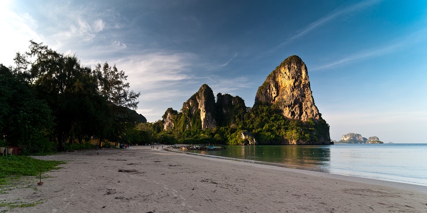 Rock climber scaling Railay Beach’s towering limestone cliffs on the places to visit near Krabi.
