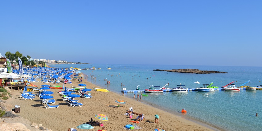 A golden sandy beach and crystal clear blue waters at Fig Tree Bay in Protaras, Cyprus.