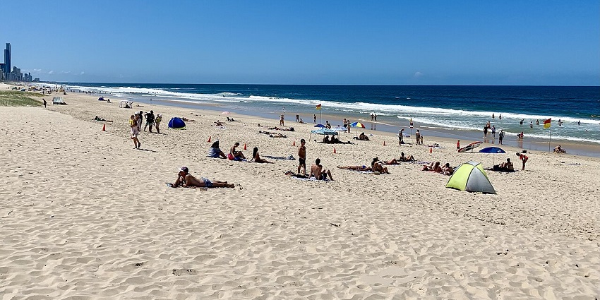 People relaxing and sunbathing at the serene Kurrawa Beach in Queensland, Australia