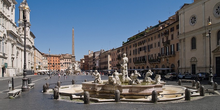A vibrant daytime scene at Piazza Navona in Rome, featuring the Fountain of the Four Rivers