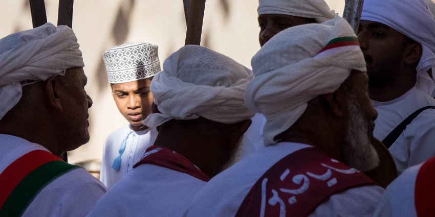 Image of Omani men in traditional attire gathering to celebrate Oman’s Renaissance Day.