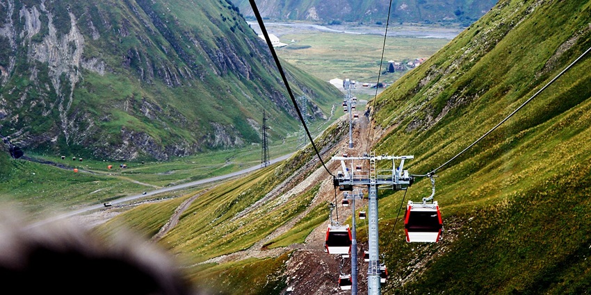 Gondola cable car gliding above snow-dusted mountains, the most scenic things to do in Kazbegi.
