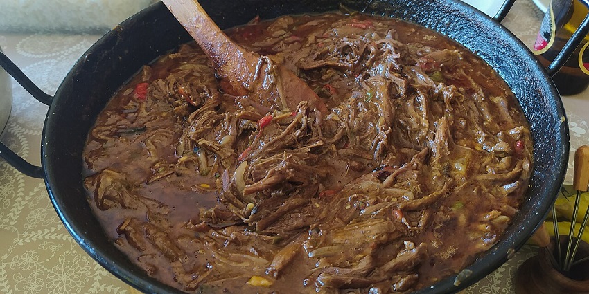 An image of a plate of Ropa Vieja with shredded beef, rice, and plantains.