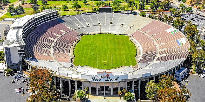 Rose Bowl stadium from above with multiple lights, empty seats and cars parked outside