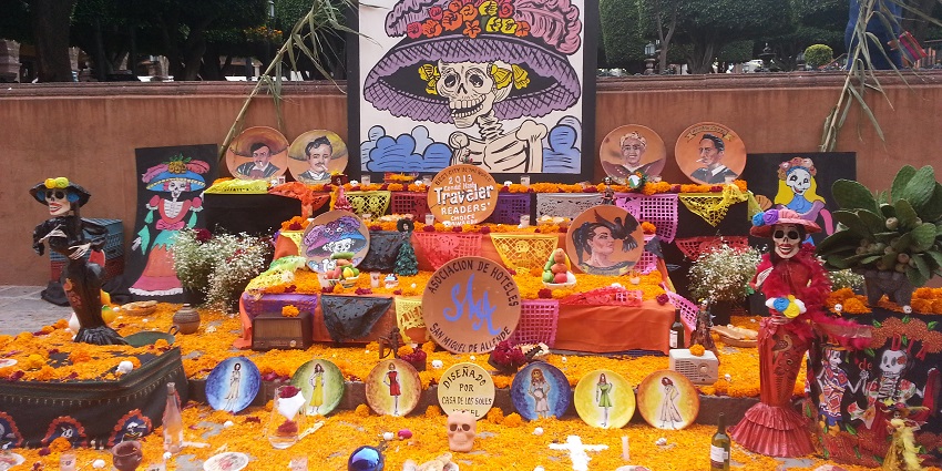 An altar covered in marigolds with skeletons and cutouts placed with offerings