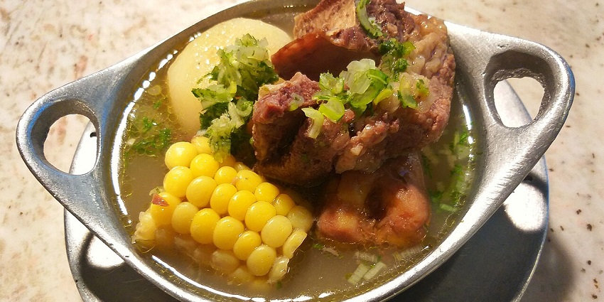 Image of a hearty bowl of Panamanian Sancocho with chicken, yam, and culantro.