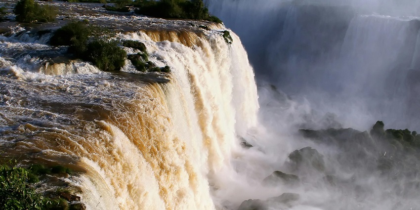 A powerful waterfall crashing down into a rocky gorge, with mist rising into the air.