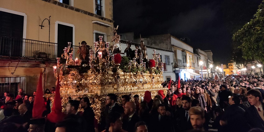Crowds gather at night for a religious procession with a grand gold float display.