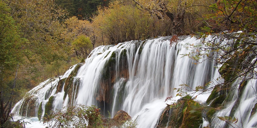 Breathtaking view of the cascading Shuzheng Waterfall surrounded by lush greenery.