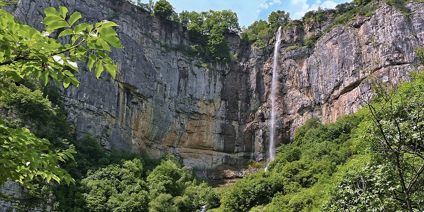 Skaklya Waterfall with water cascading dramatically from towering mountain cliffs