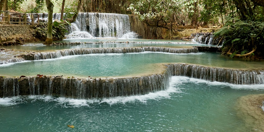 A powerful stream of Falls surrounded by snow-dusted cliffs and evergreen forest.
