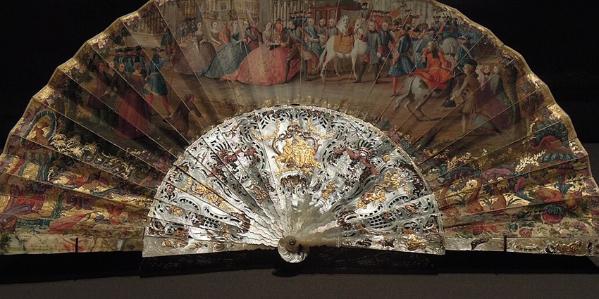 An image of a woman holding a fan resembling a Spanish fan, a famous thing to buy in Spain.