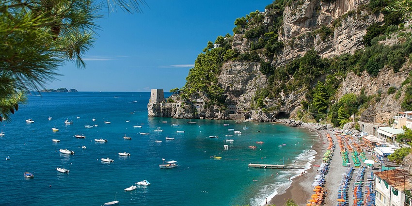 Peaceful view of Fornillo Beach with cliffs, clear waters, and beachside cafés in Positano.