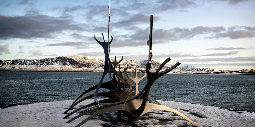 Things to do in Reykjavik include taking a scenic walk by the sea with views of Mt. Esja and glowing skies during the golden hour.