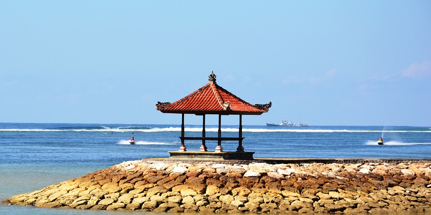A charming wooden-roofed gazebo in Tanjung Benoa Beach with stunning sunset views.