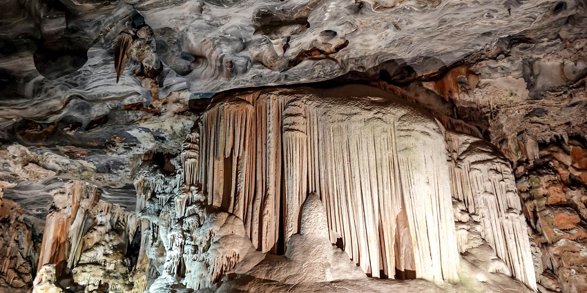 Inside Cango Caves in Oudtshoorn, illuminated mineral deposits adorn the limestone walls