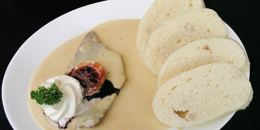 An image of Svíčková na smetaně served with sauce and bread dumplings.