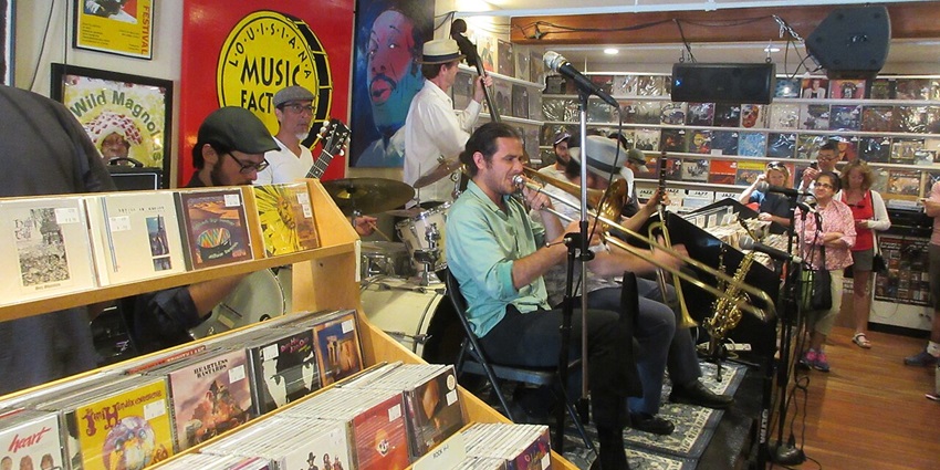 Live band performing at a cosy bar with neon signs and an engaged, relaxed audience nearby.