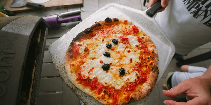 A picture of a tourist preparing a pizza at a cooking class in Rome, Italy